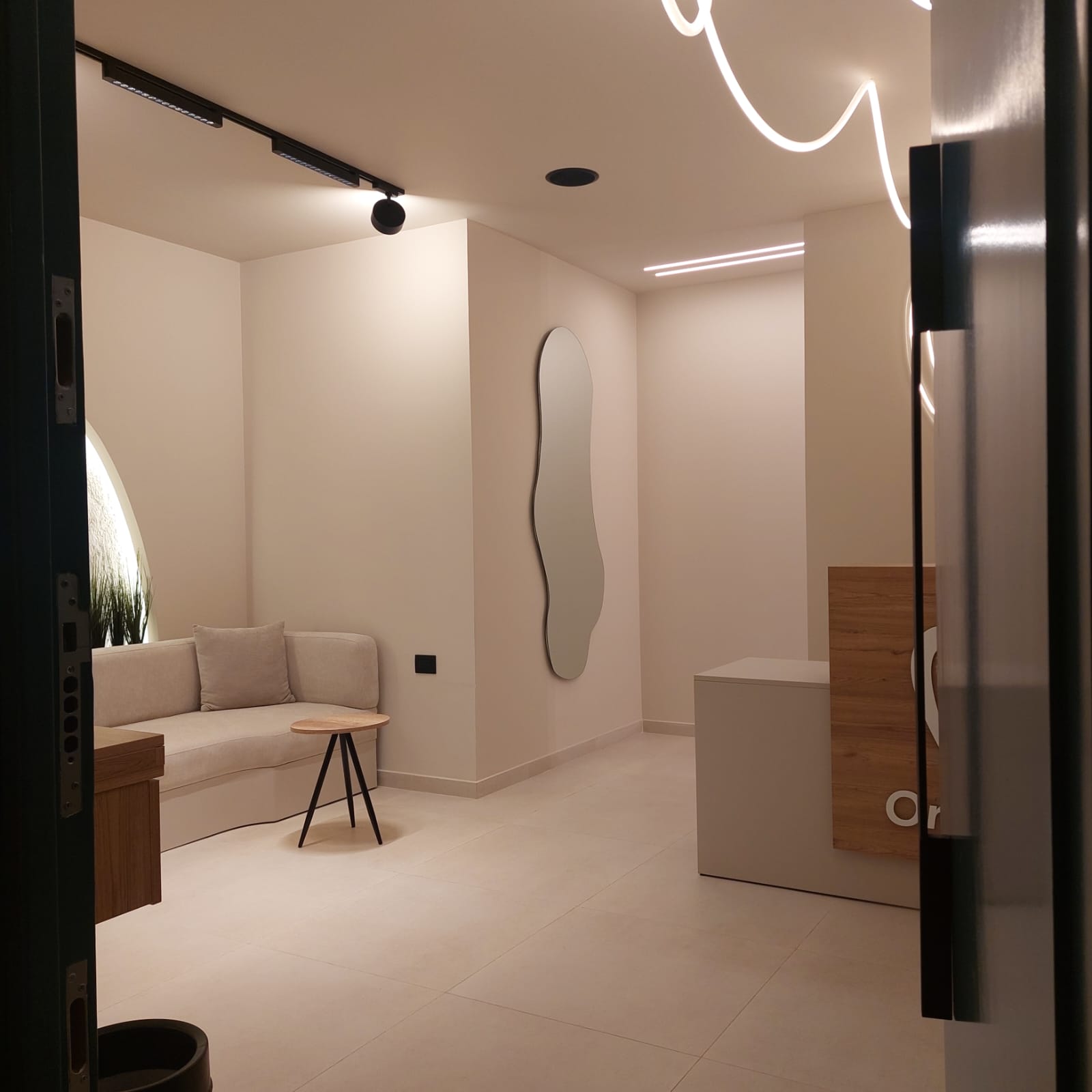 Dental clinic entrance with built-in sofa, organic mirror and reception desk