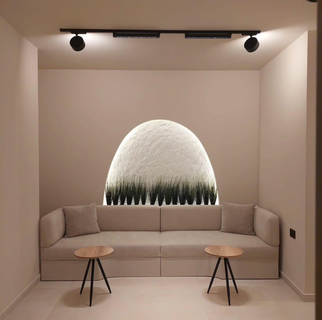 Waiting lounge with built-in sofa and backlit textured arch niche