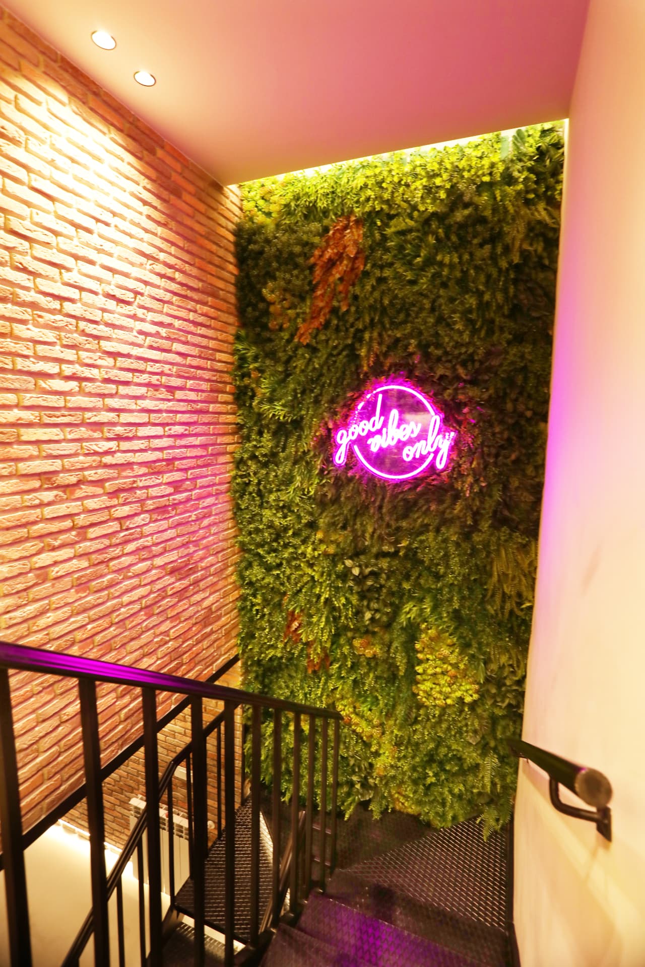 Stairwell with brick wall, plant wall and neon sign