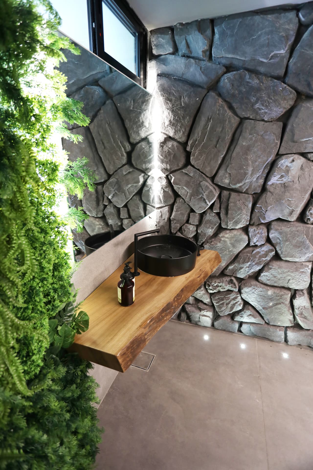 Powder room with stone wall, live-edge timber vanity and plant wall
